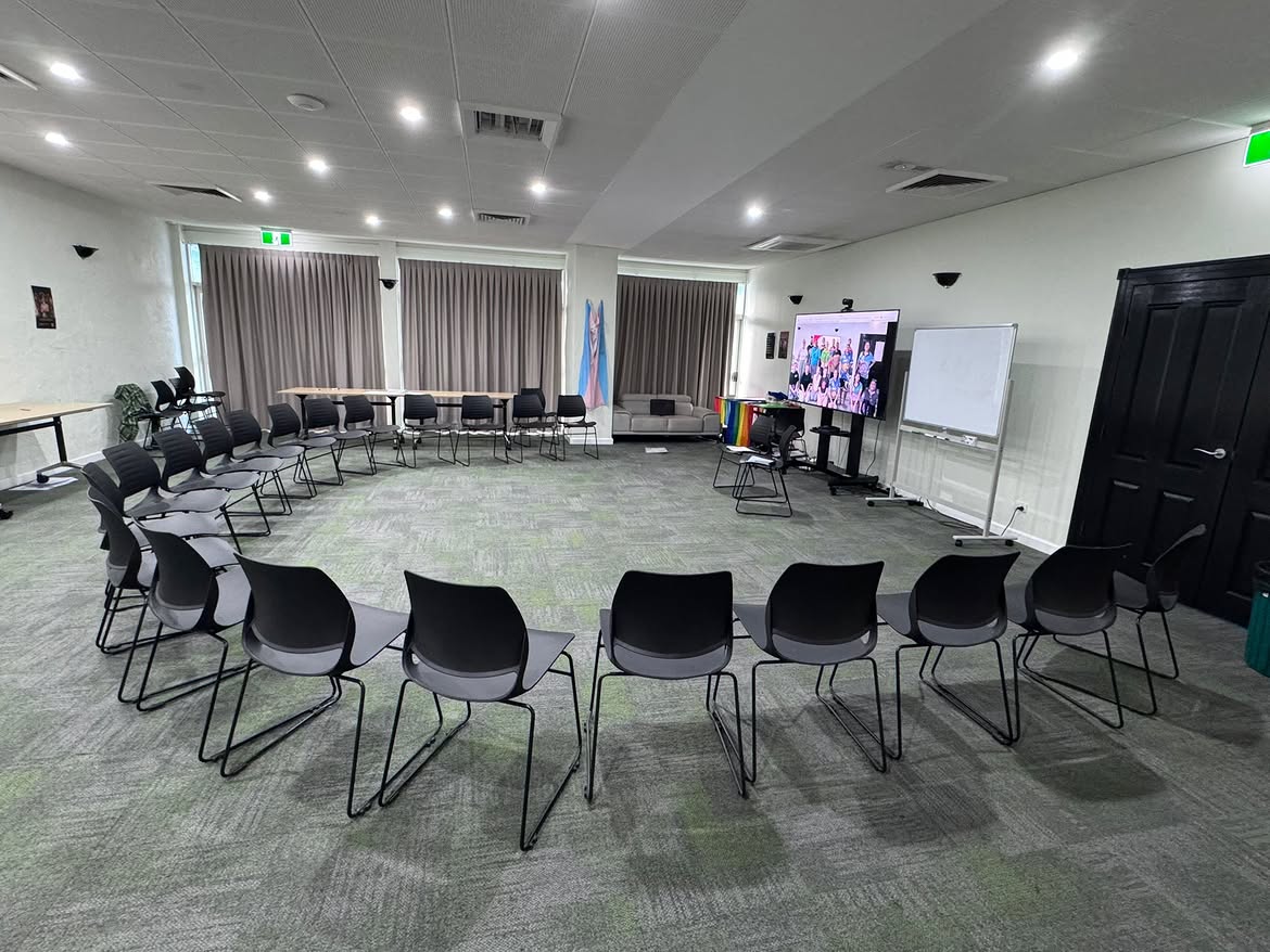 Katherine Motel training room arranged in a circle of chairs with large presentation TV, whiteboard and breakout tables